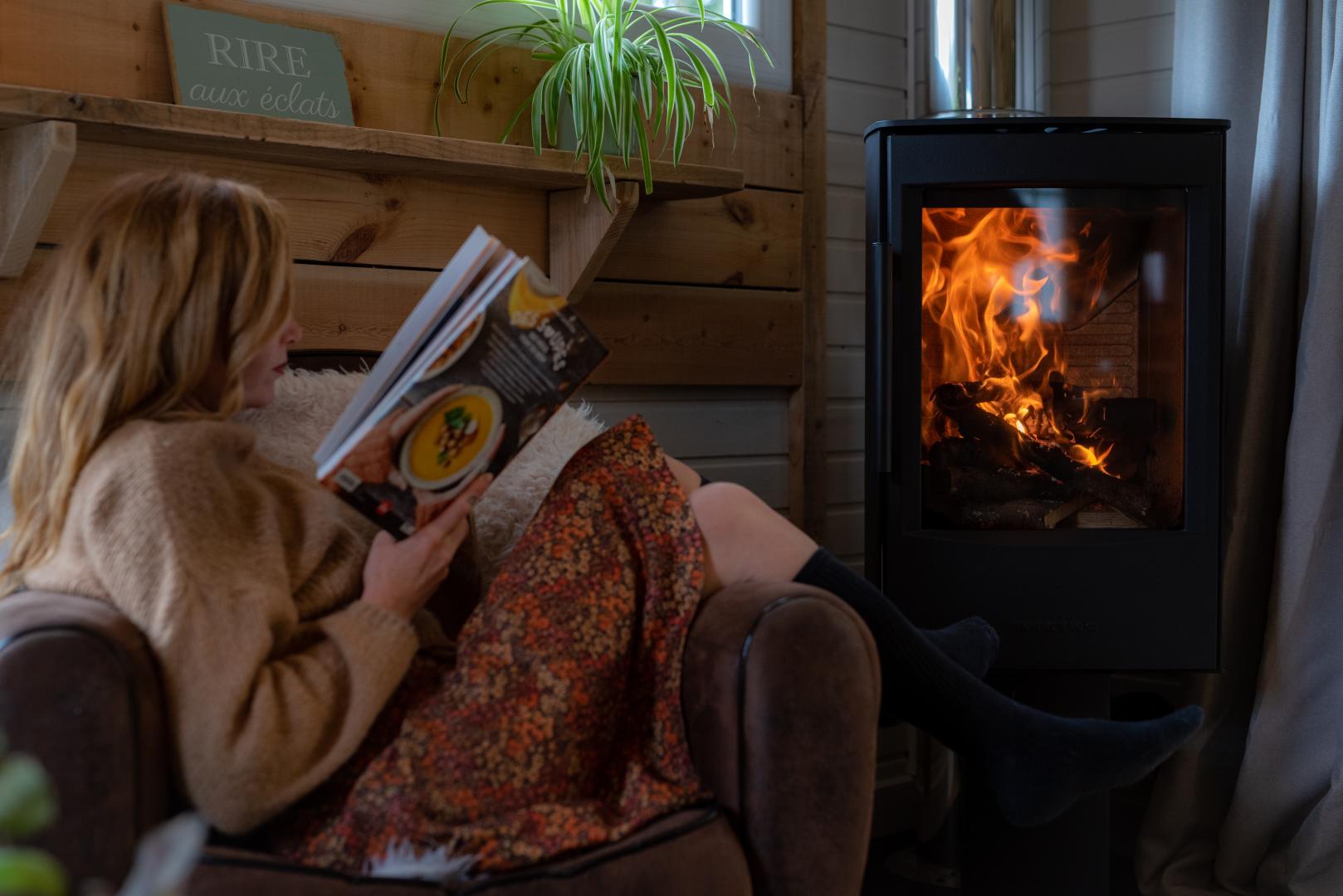 Moment de lecture au coin du poêle à bois, sans écran, dans le chalet